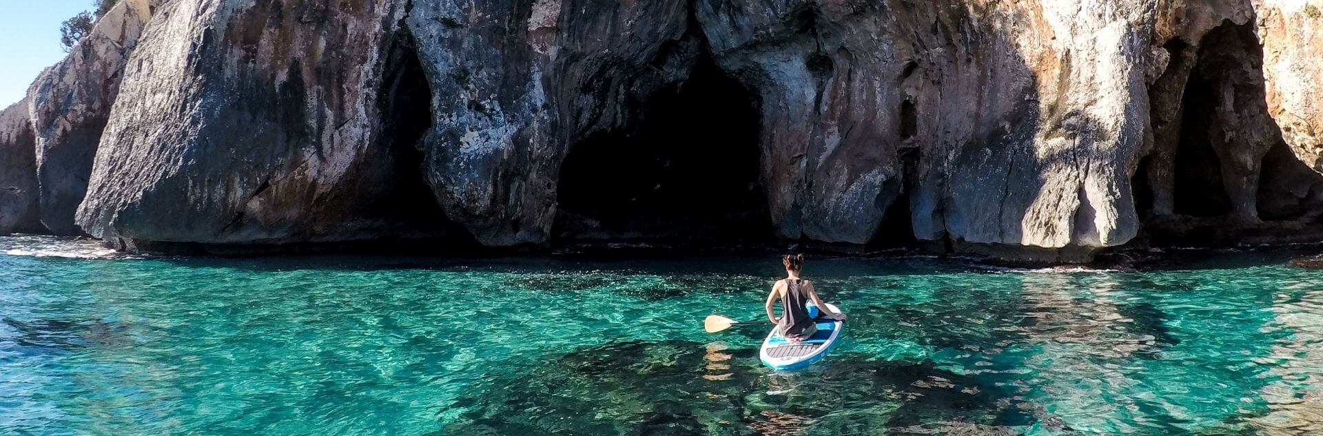 Frau sitzt auf SUP im Meer Sardinien