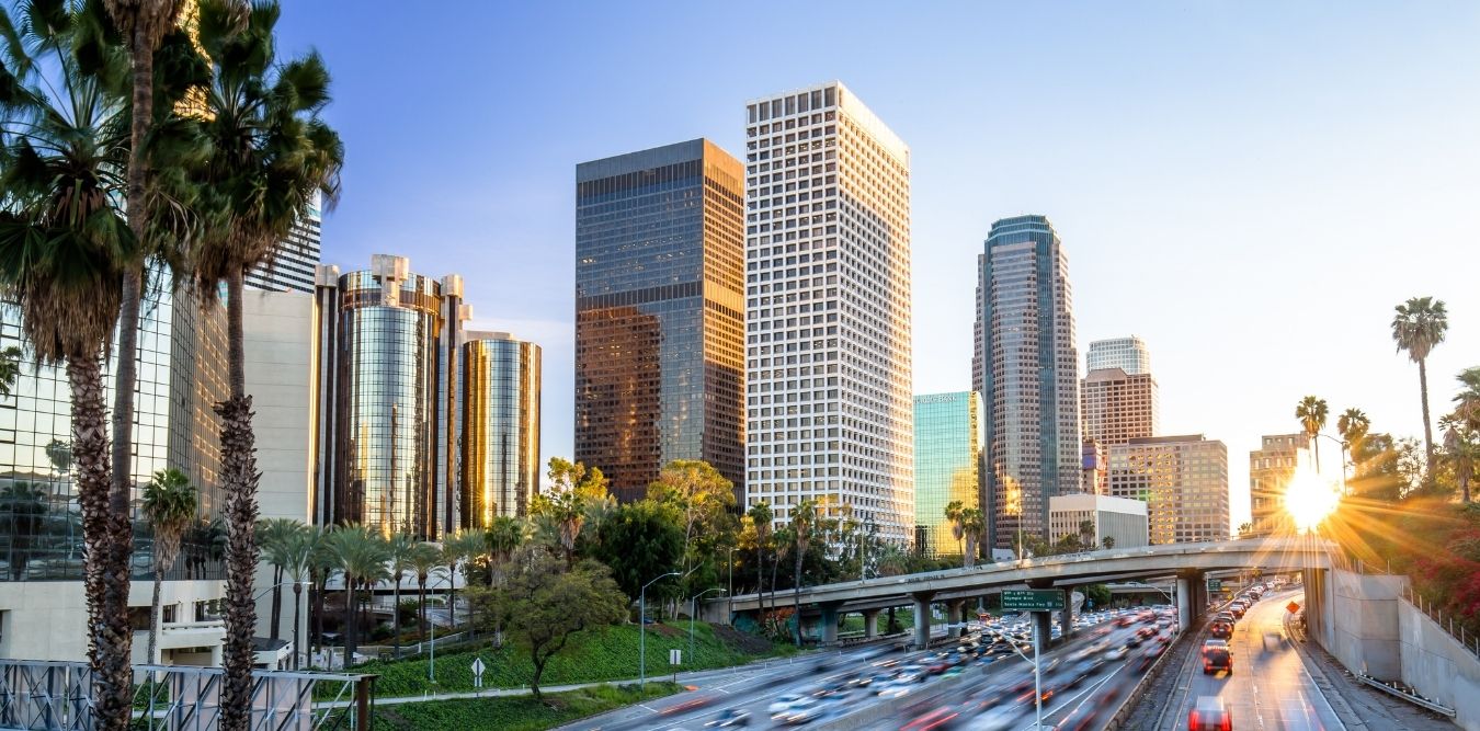 Los Angeles Downtown mit Hochhäusern und Palmen bei Sonnenuntergang