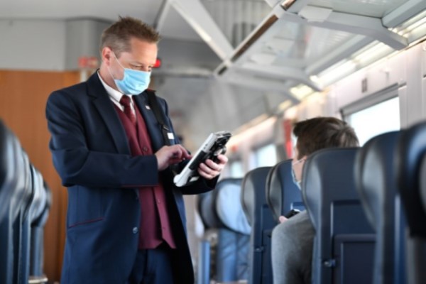 Deutsche Bahn Schaffner mit Maske kontrolliert Fahrgast