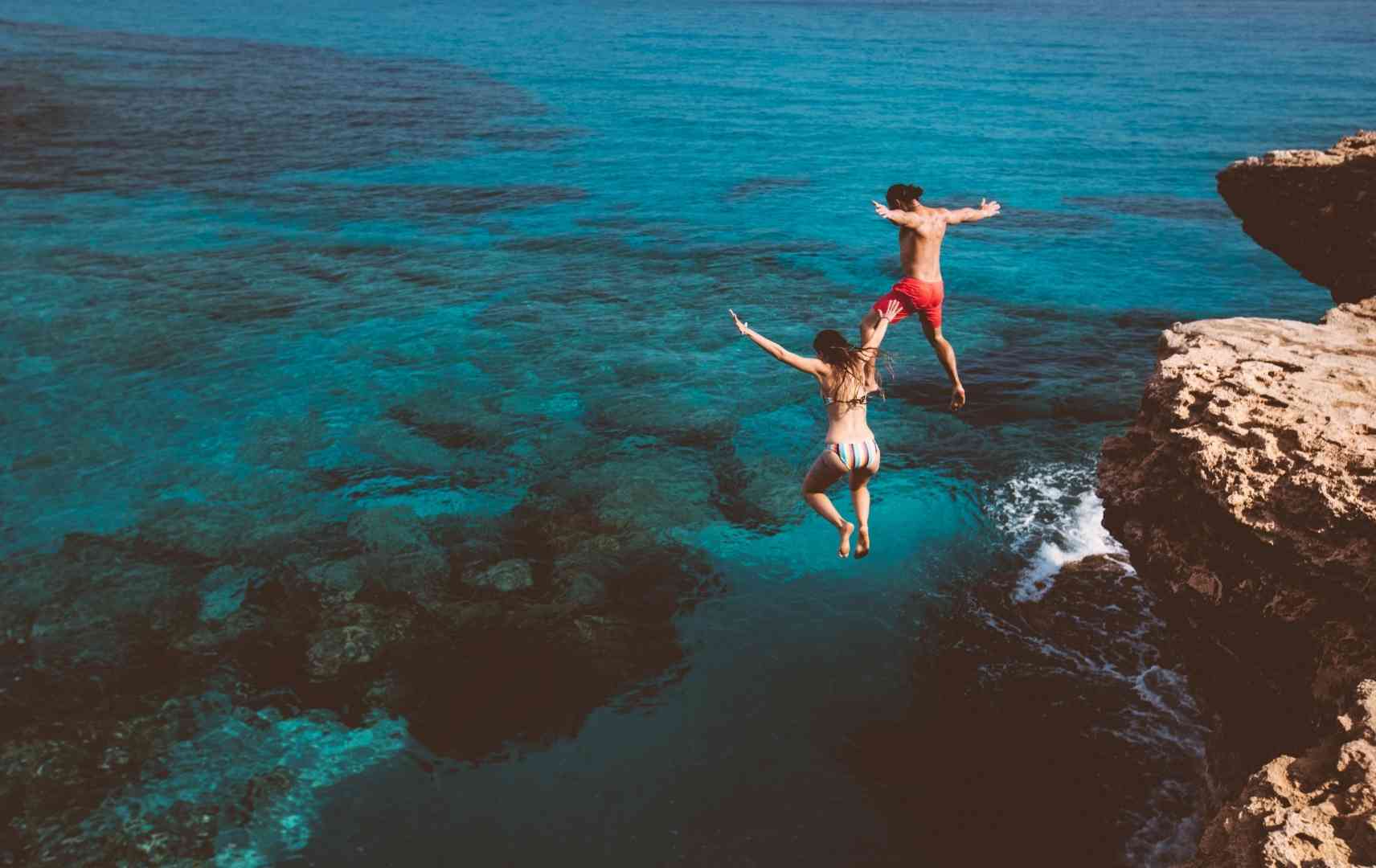 Paar springt ins Meer im Sommerurlaub
