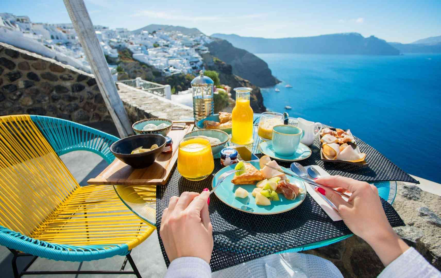Frau beim Frühstück im Urlaub mit Meerblick