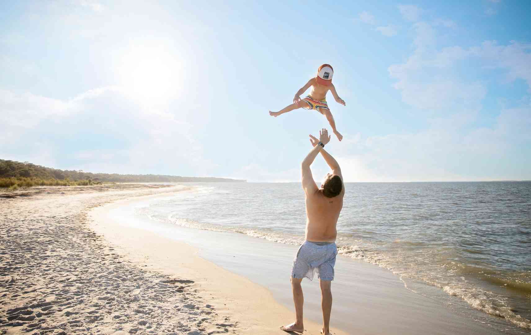 Vater mit Sohn am Strand im Familienurlaub