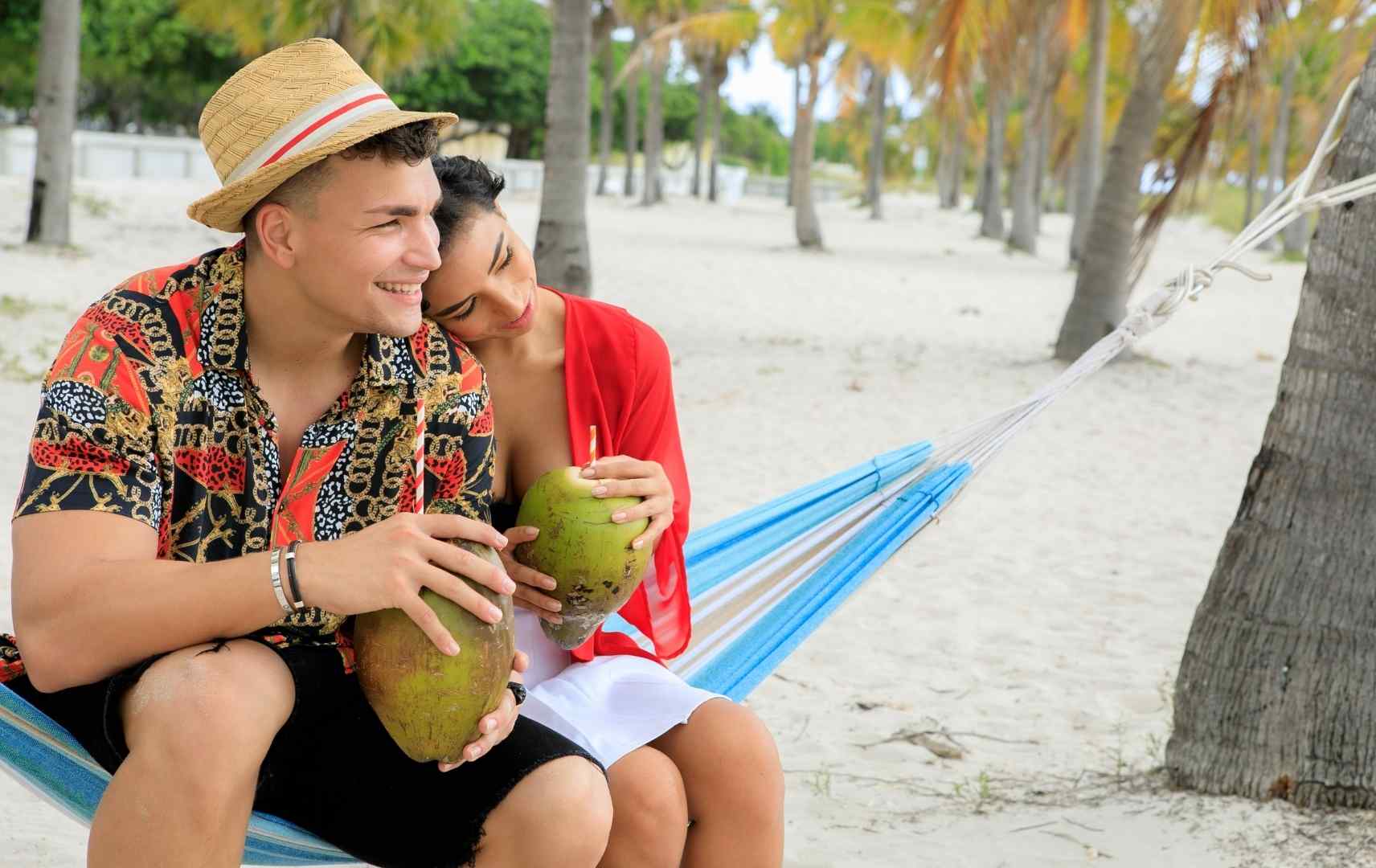 Paar sitzt in Hängematte und trink aus Kokosnuss