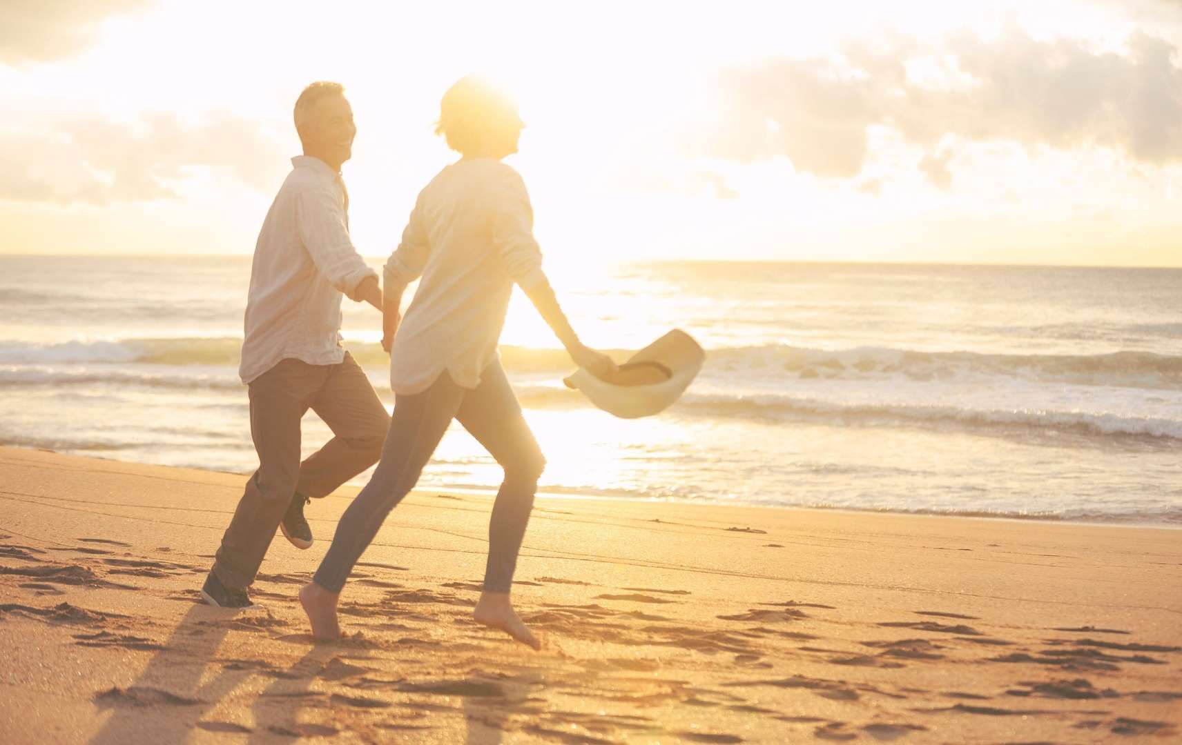 Paar läuft Hand in Hand am Strand im Sonnenuntergang