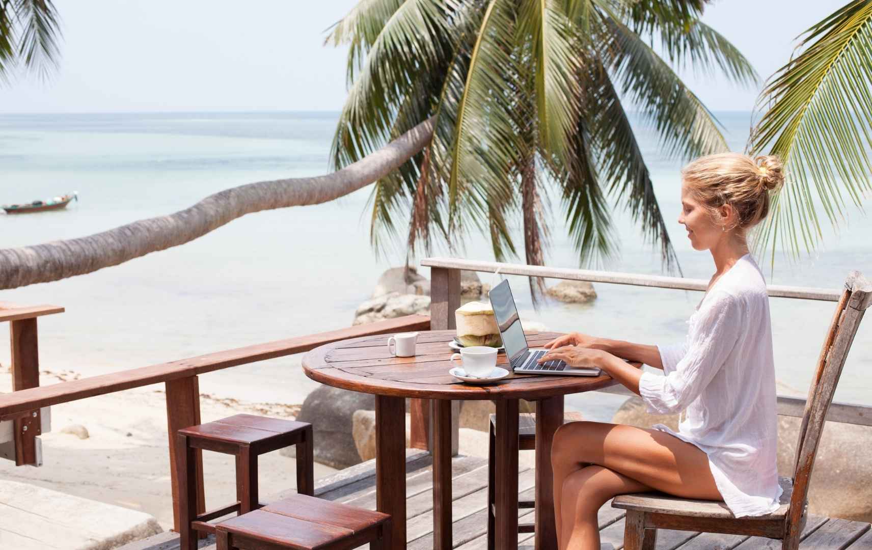 Frau mit Laptop und Getränken am Strand