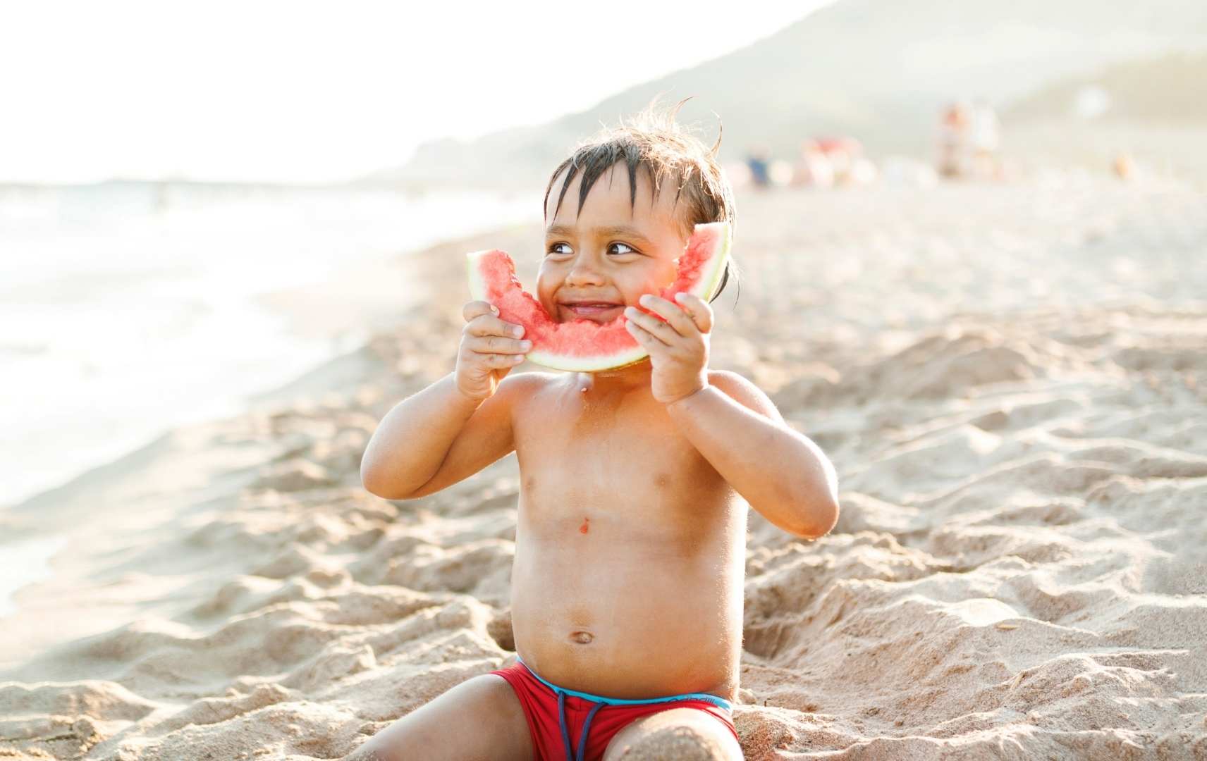 Junge am Strand mit Wassermelone