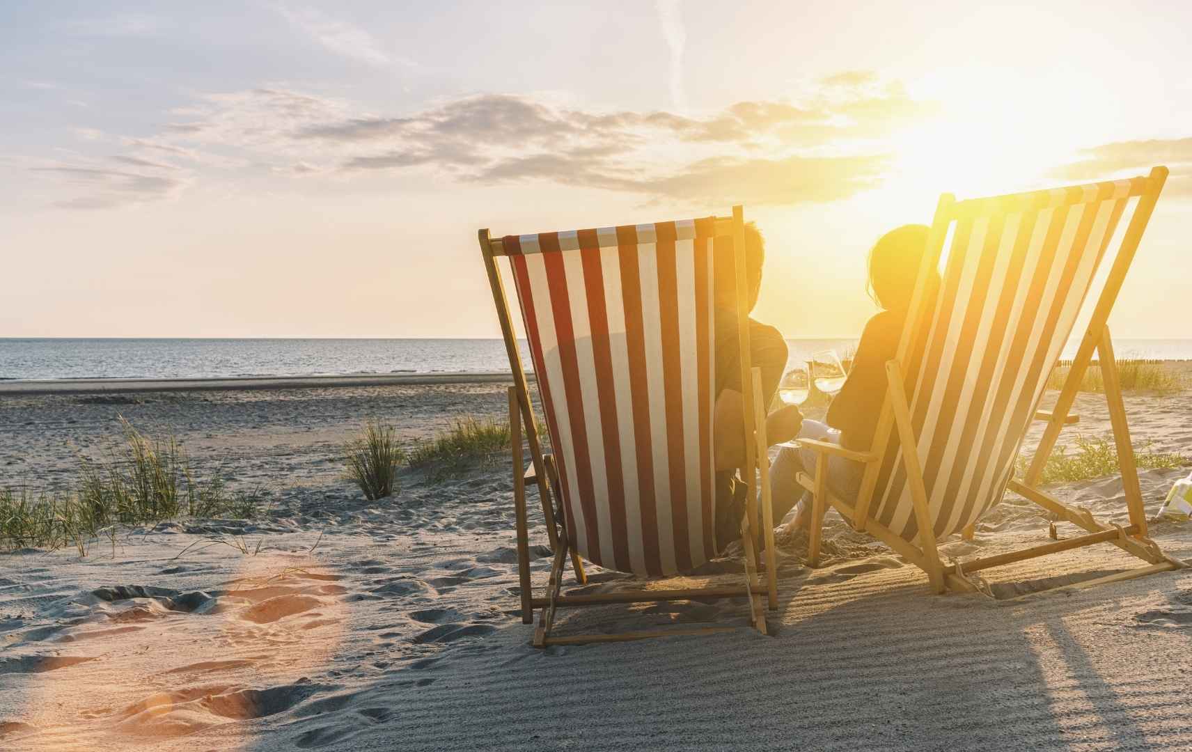 Paar am Strand in Strandstühlen zum Sonnenuntergang