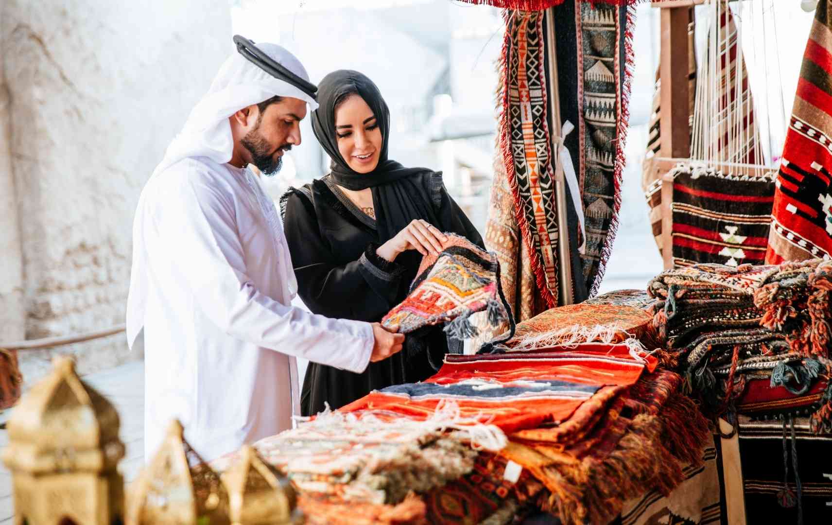Mann und Frau auf Souk mit Teppichen in Dubai
