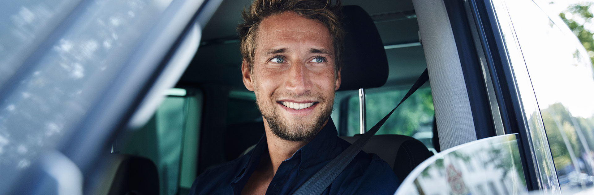 Lächelnder junger Mann in einem Auto