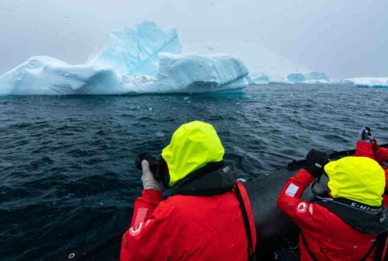 Zwei Personen fotografieren einen Eisberg