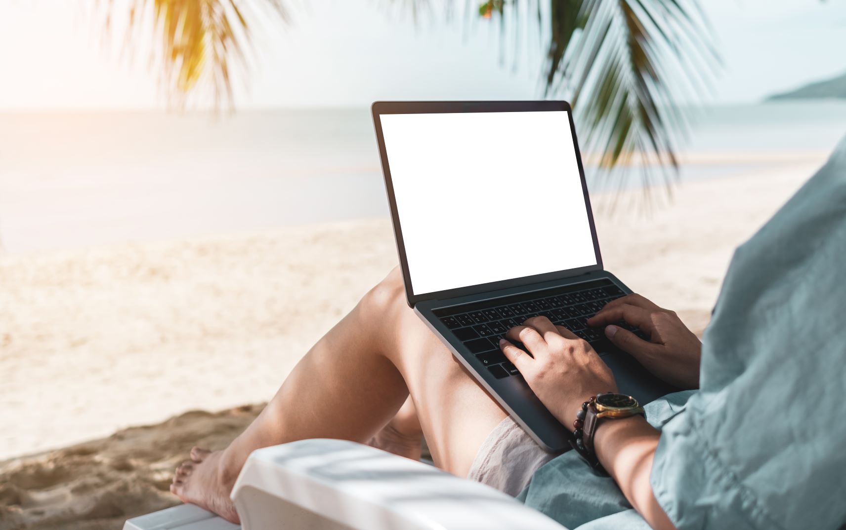 Am Strand arbeiten unter Palmen mit Laptop