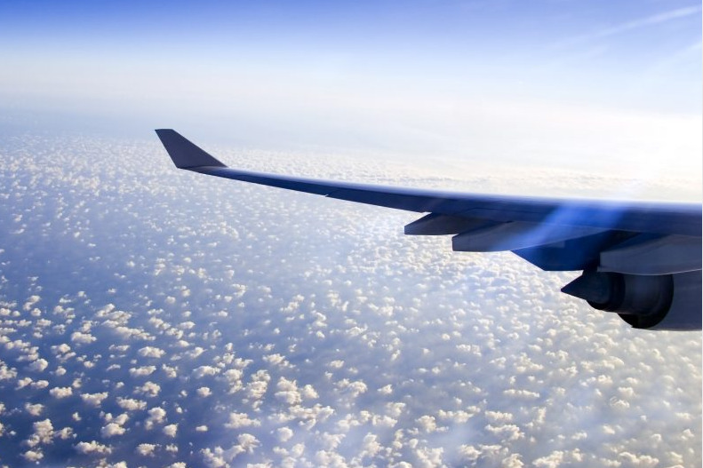 Flugzeug in der Luft über einer aufgelockerten Wolkendecke