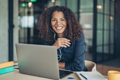Businesswoman with laptop and ear phones smiling