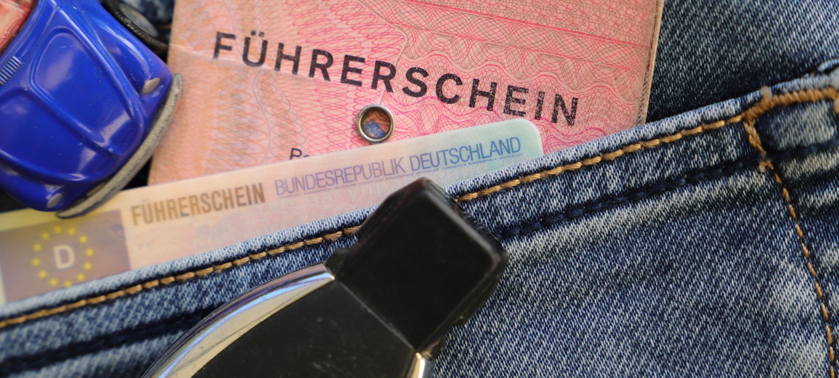 Alter EU-Papierführerschein und neuer EU-Kartenführerschein in einer Hosentasche zusammen mit einem Autoschlüssel